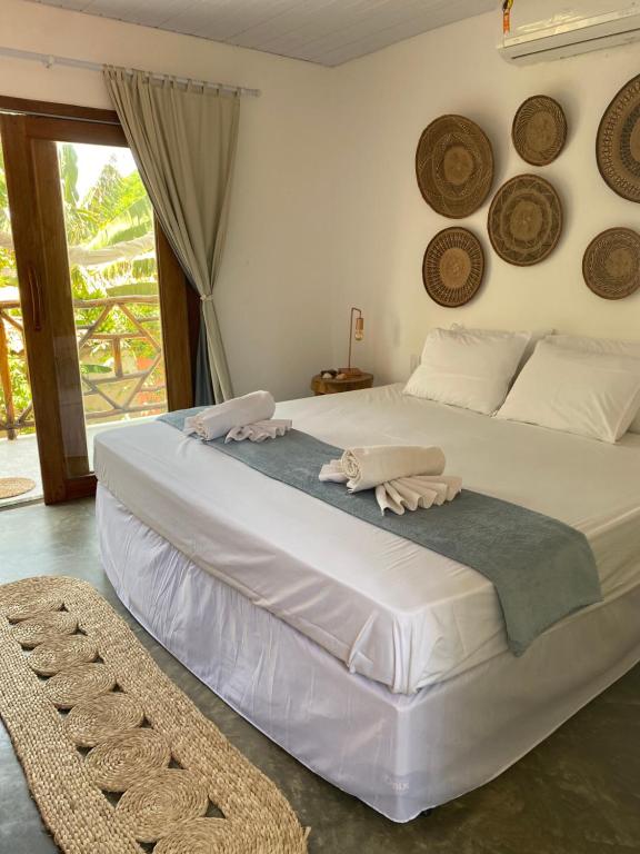 um quarto com uma grande cama branca com chapéus na parede em Casa Éolica em Barra Grande
