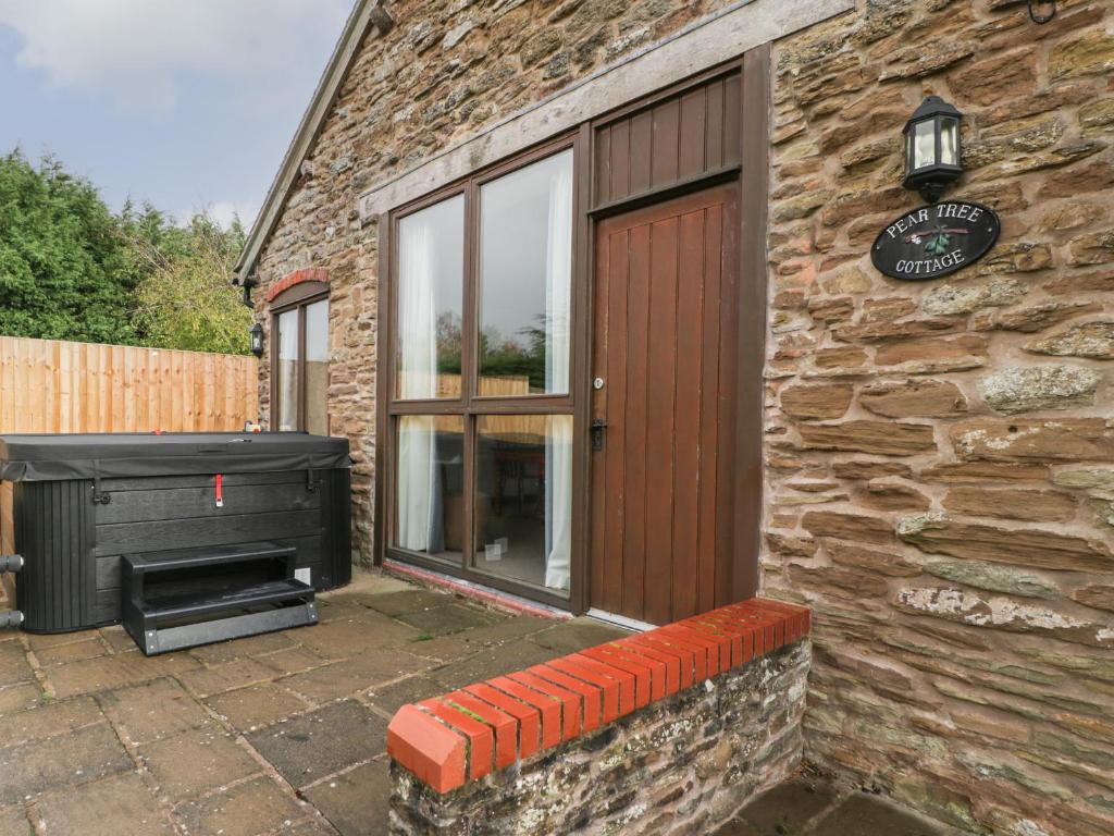 a stone building with a door and a grill at Peartree Cottage in Worcester