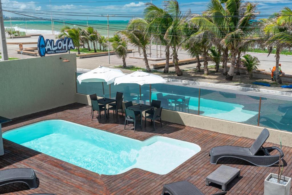 a swimming pool with tables and chairs and the beach at Hotel Pousada Aloha in Maceió