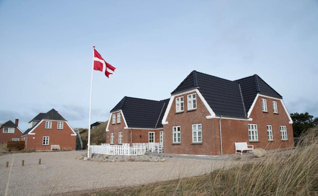 亨能史特蘭德的住宿－Det Gamle Badehotel - Klitgaarden，前面有旗帜的房子