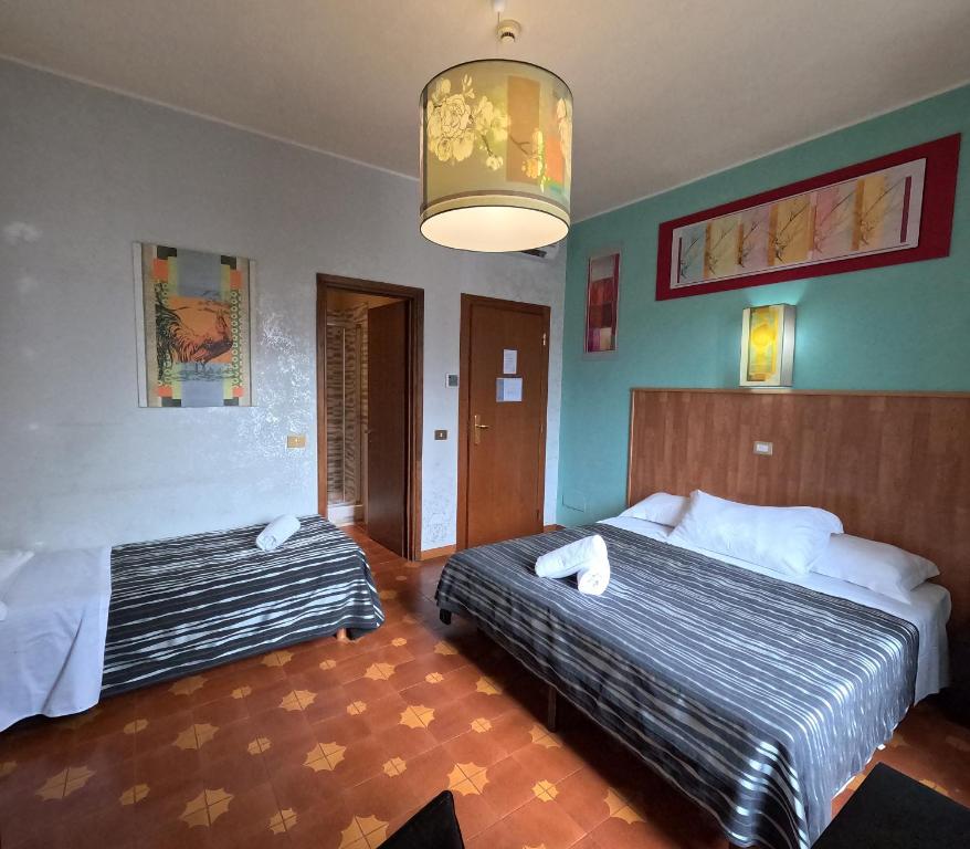 a hotel room with two beds and a chandelier at Roma Room Hotel in Rome