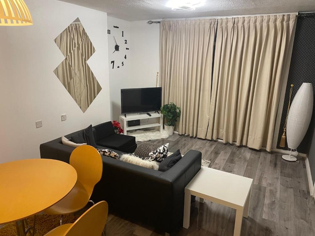 a living room with a black couch and a tv at Two bedroom flat in London near the 02 in London
