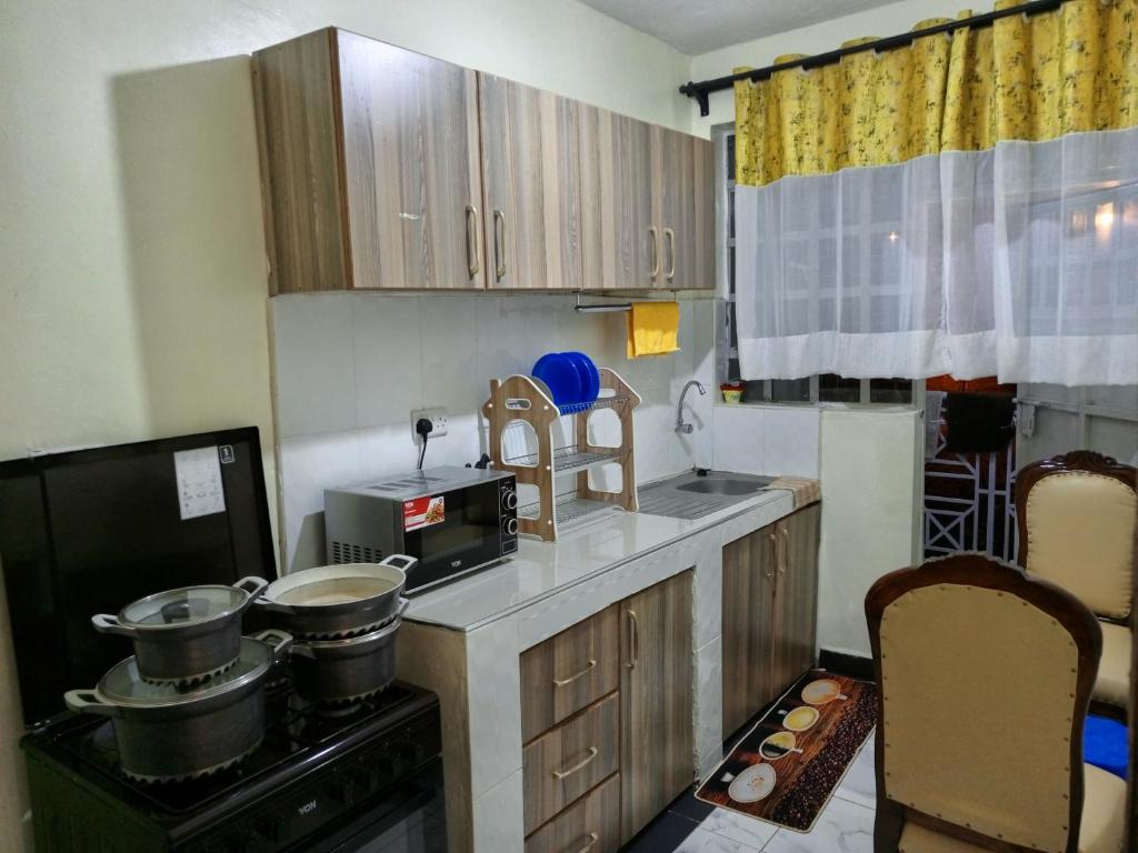 a small kitchen with a stove and a microwave at SAFNEST Furnished Apartment in Nakuru