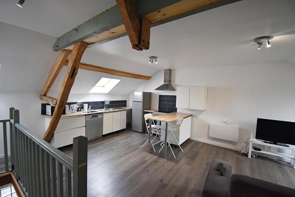 une cuisine mansardée avec des placards blancs et une table dans l'établissement Bel appartement 2 chambres climatisé, à Mont-Notre-Dame