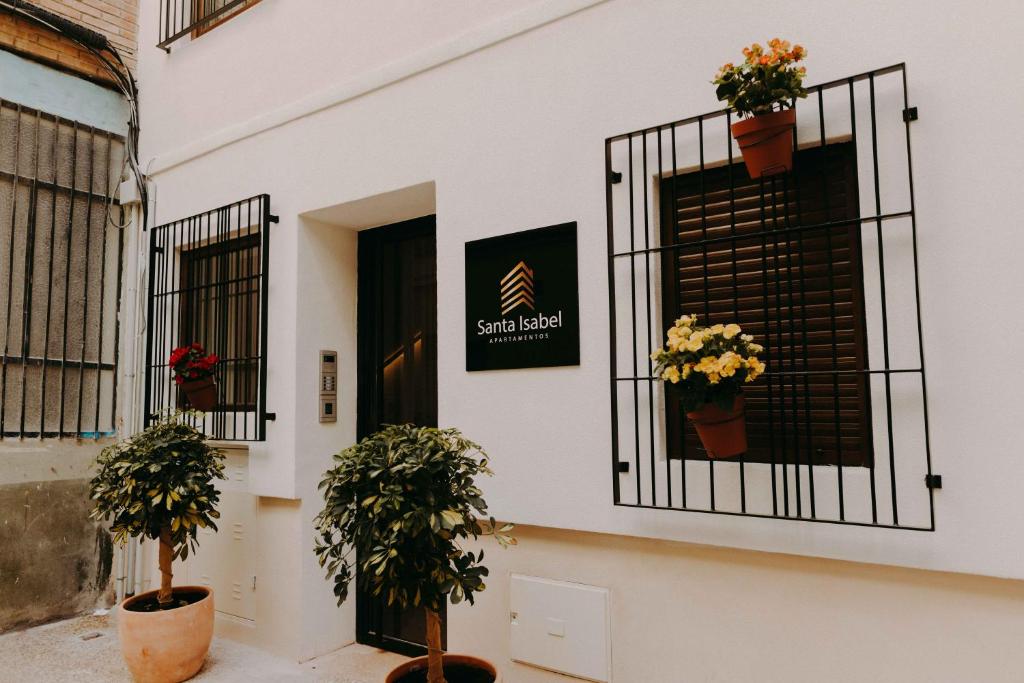 un edificio blanco con macetas en la puerta en Apartamentos Santa Isabel en Murcia