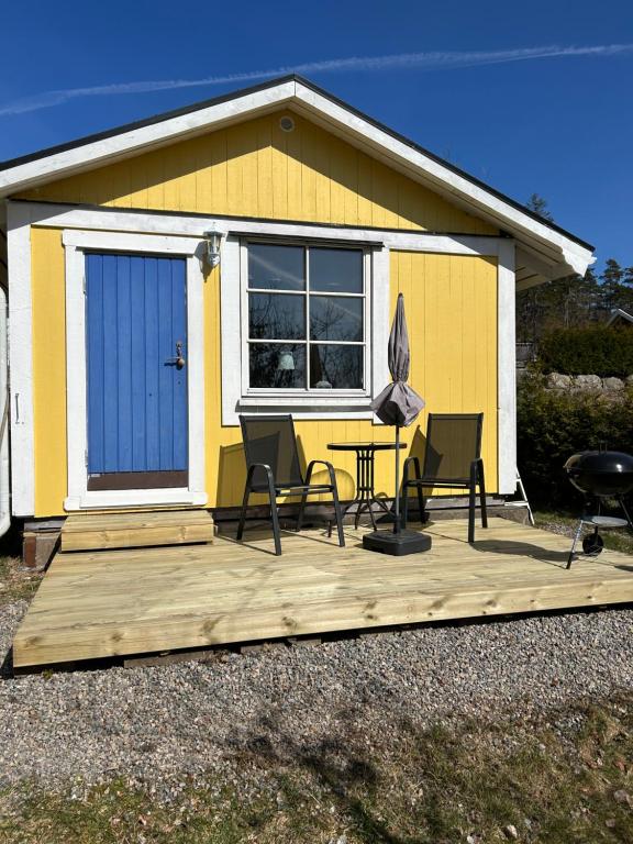 a house with a deck with chairs and an umbrella at Söt liten stuga för 2 in Strömstad
