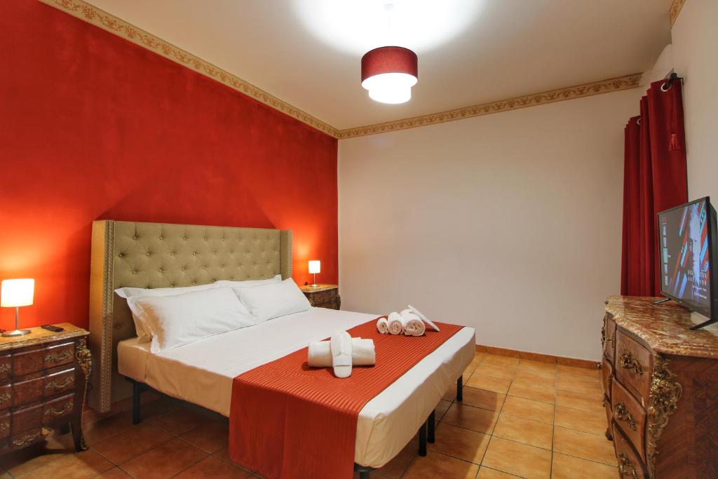 um quarto com uma cama com uma parede vermelha em Biscione Large Apartment - Campo de Fiori by YourHost em Roma