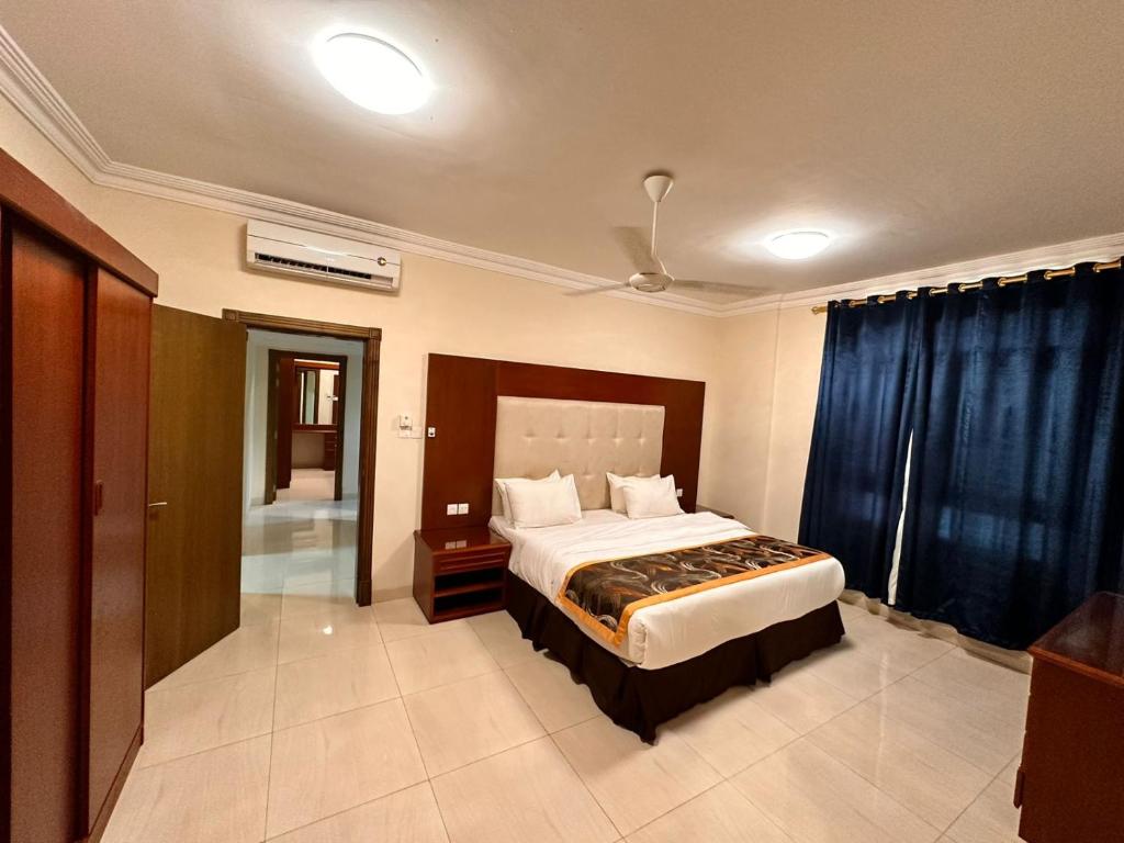 a bedroom with a large bed with blue curtains at Star Apartments in Salalah