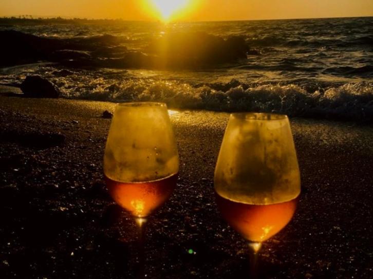 two wine glasses sitting on a beach with the ocean at La Racioppola in Ostuni