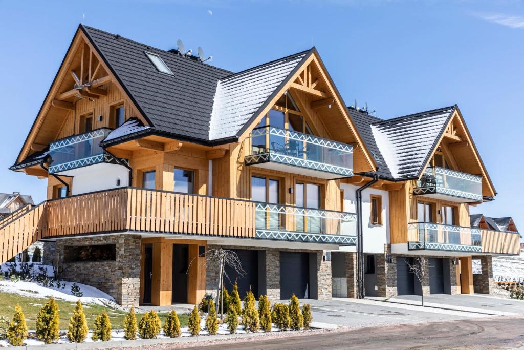 a large wooden house with a black roof at Apartament Czorsztyn 2 in Kluszkowce