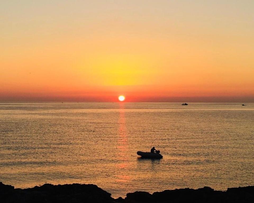 a person in a boat in the ocean at sunset at La Racioppola in Ostuni