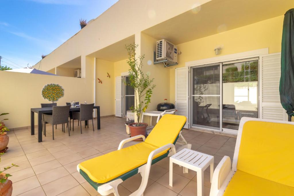 a patio with yellow furniture and a table and chairs at Casa Amiga in Praia do Carvoeiro