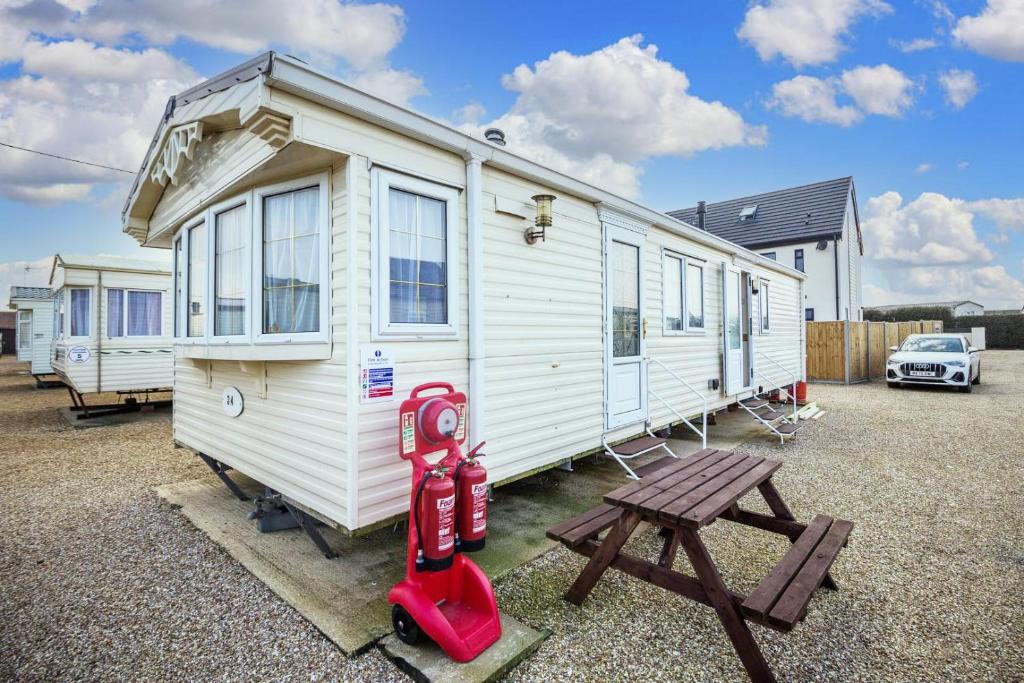 a small white trailer with a wooden table and a bench at 6 Berth Pet Friendly Caravan In Hunstanton By The Beach Ref 13001l in Hunstanton