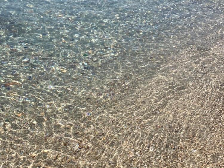 a close up of the sand and water on a beach at La Racioppola in Ostuni