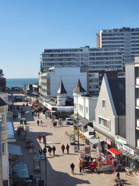 un grupo de personas caminando por una calle con edificios en Hotel von Stephan en Westerland