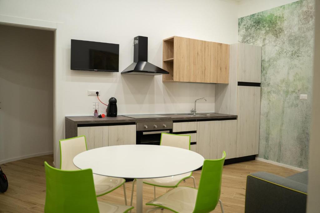 une cuisine avec une table blanche et des chaises vertes dans l'établissement Salerno City Apartments, à Salerne