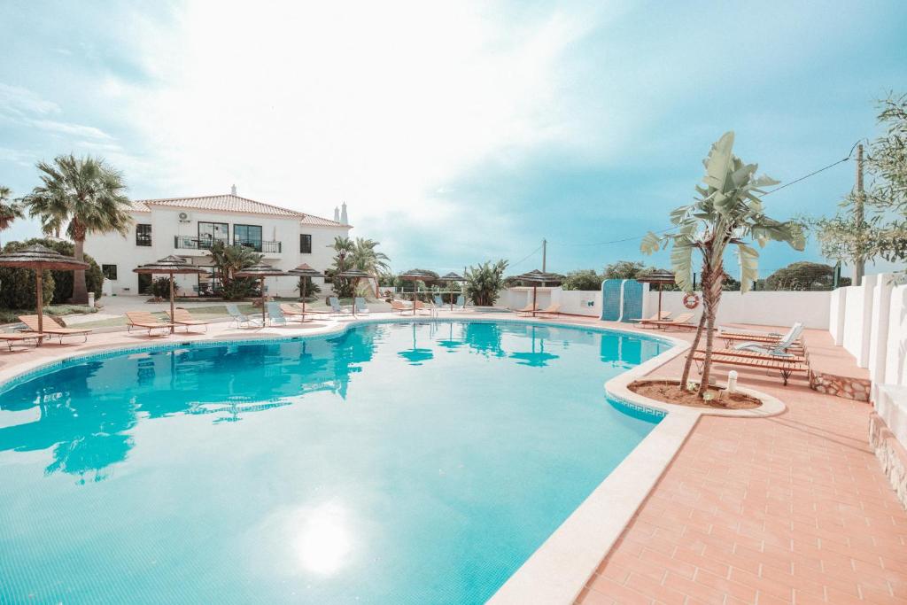 a swimming pool at a resort with chairs and a palm tree at Casa Velha Apartments - Adults friendly in Albufeira
