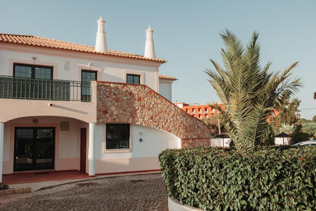 a house with a palm tree in front of it at Casa Velha Apartments - Adults friendly in Albufeira