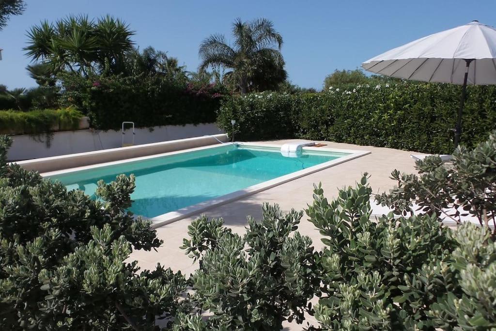 una piscina con ombrellone in un cortile di Villa Alessandra a Monopoli