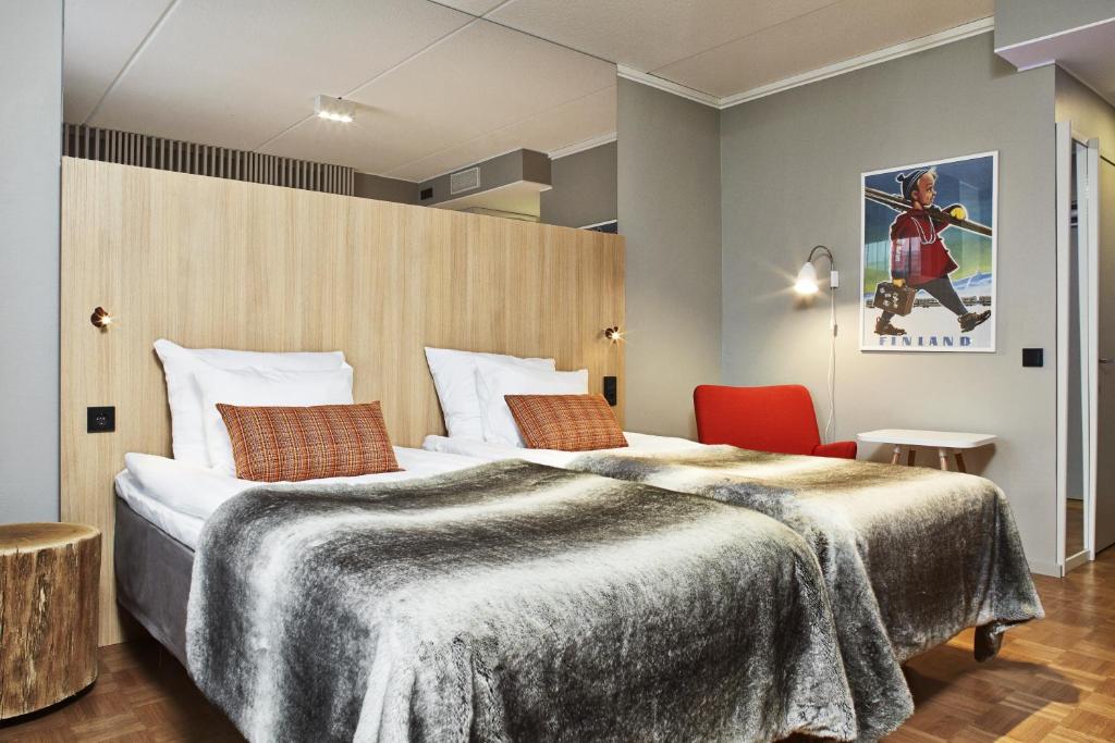 a hotel room with a large bed and a red chair at Original Sokos Hotel Vaakuna Rovaniemi in Rovaniemi