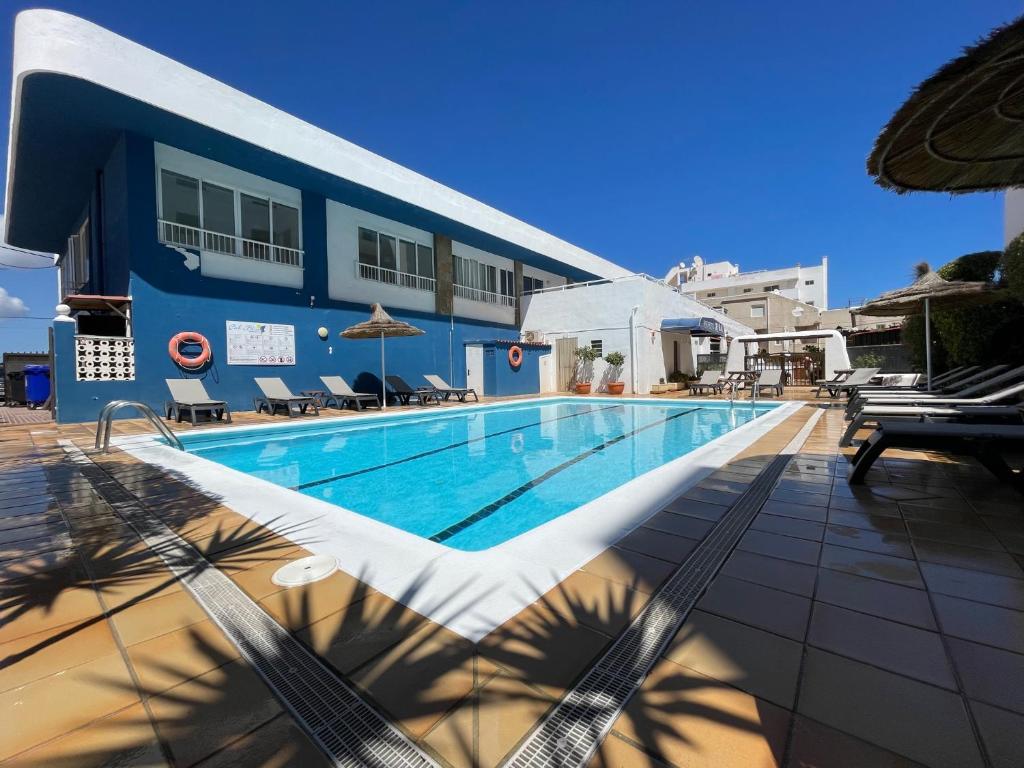a swimming pool in front of a blue building at Apartamentos Cel Blau in Es Cana