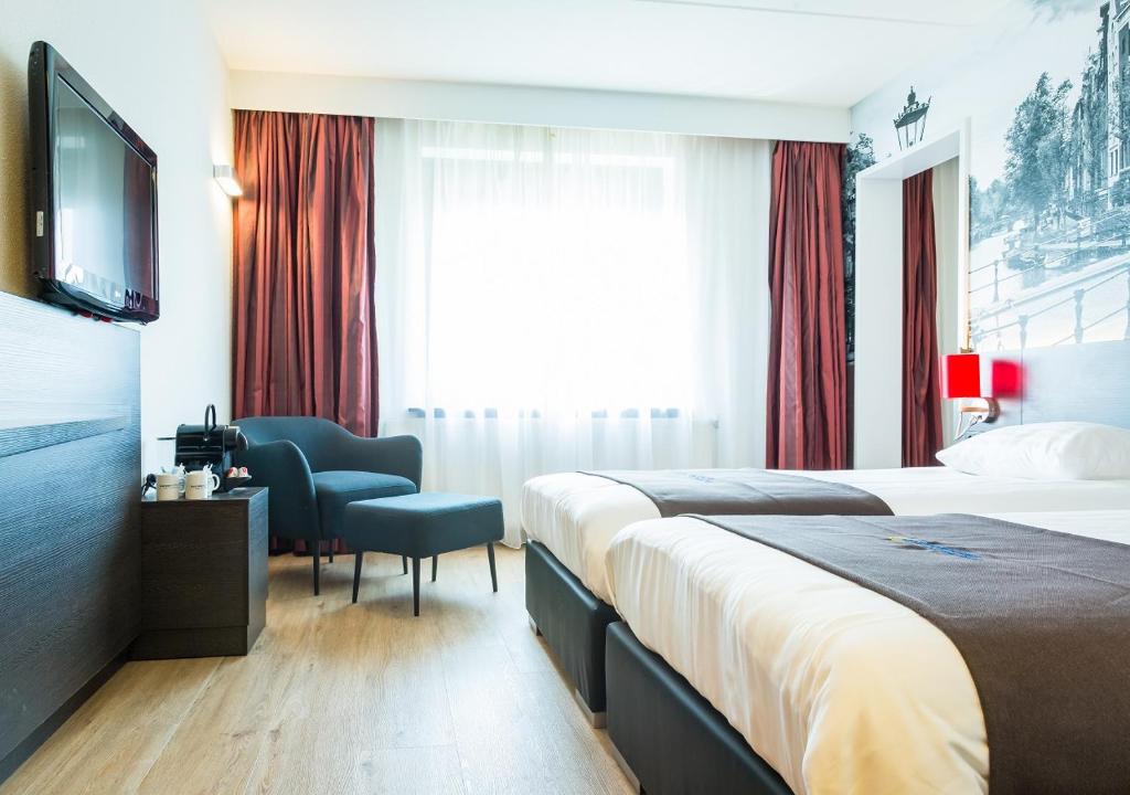 a hotel room with two beds and a television at Bastion Hotel Amsterdam Amstel in Amsterdam