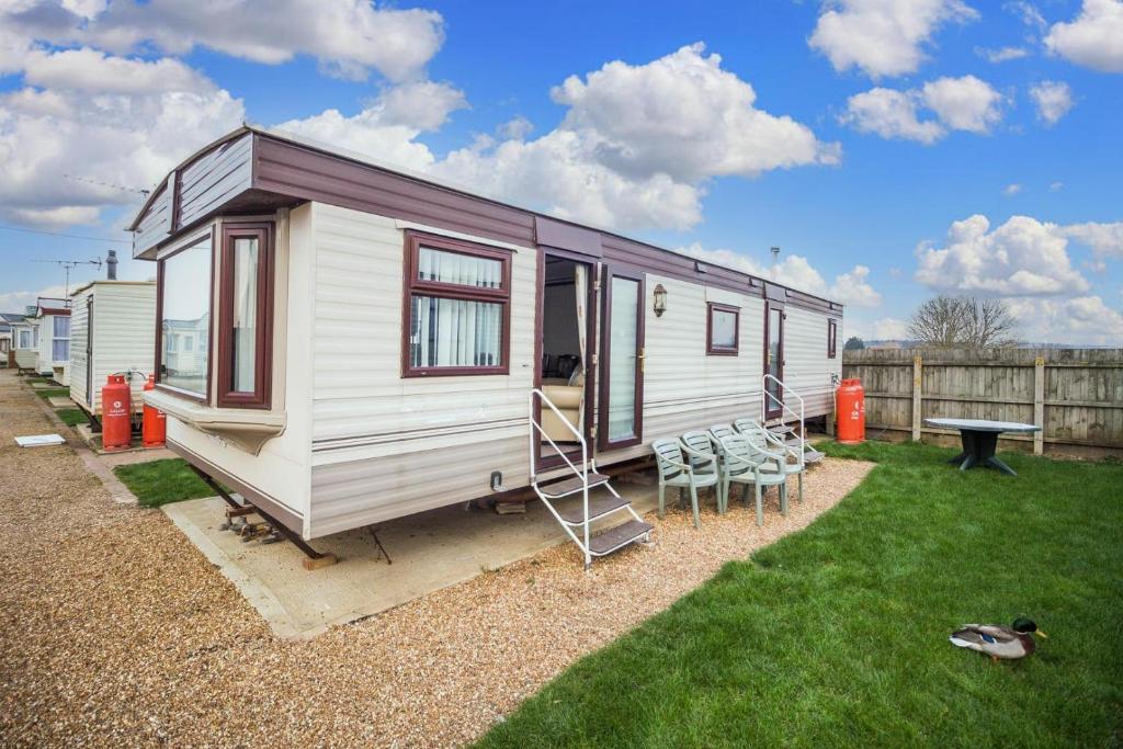a small white trailer with a table and chairs at Dog Friendly 6 Berth Static Caravan By The Beach In Hunstanton Ref 13008l in Hunstanton