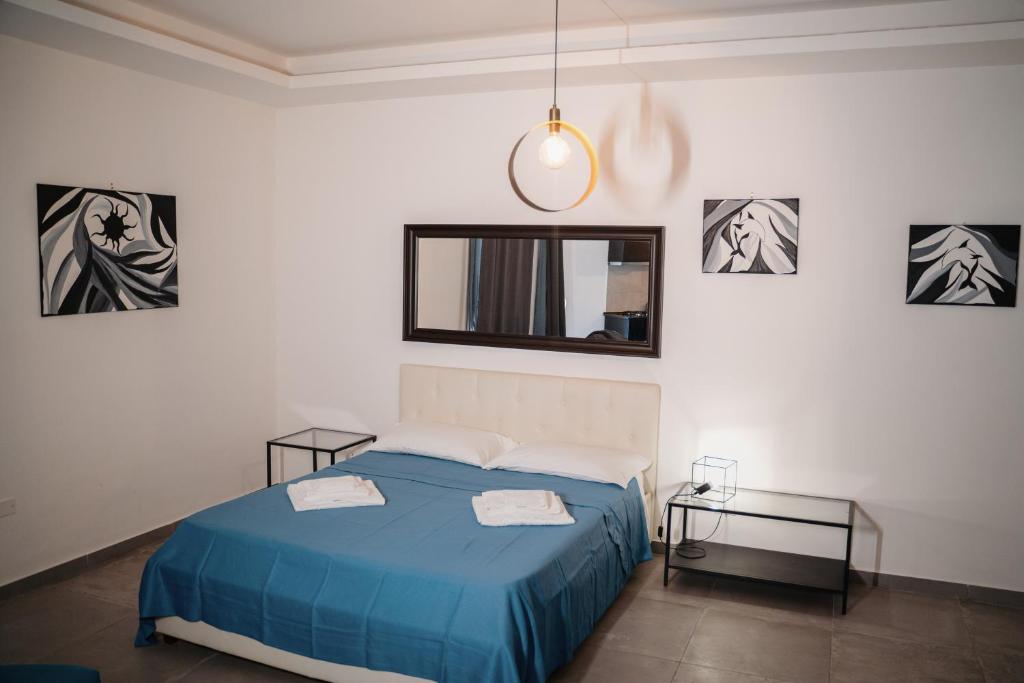 1 Schlafzimmer mit einem blauen Bett und 2 Tischen in der Unterkunft Salerno Holiday Homes in Salerno
