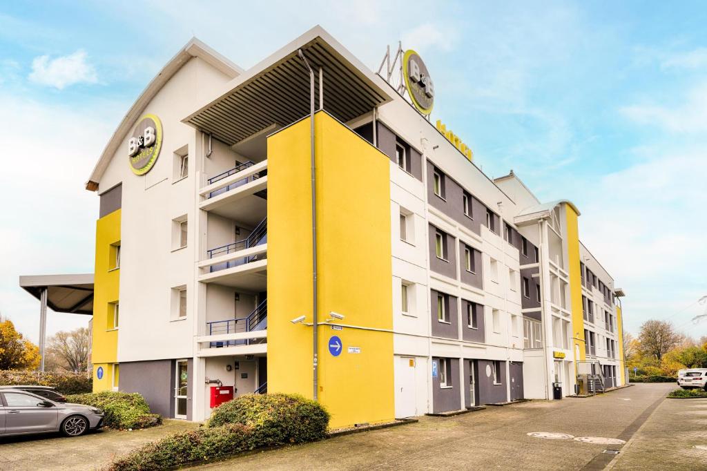 ein gelbes und weißes Gebäude mit einem Parkplatz in der Unterkunft B&B HOTEL Köln-Frechen in Frechen