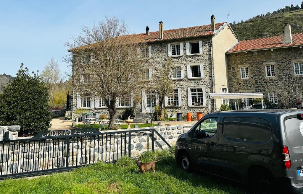 um carro estacionado na relva em frente a um edifício em HL Hotel de la Loire em Goudet