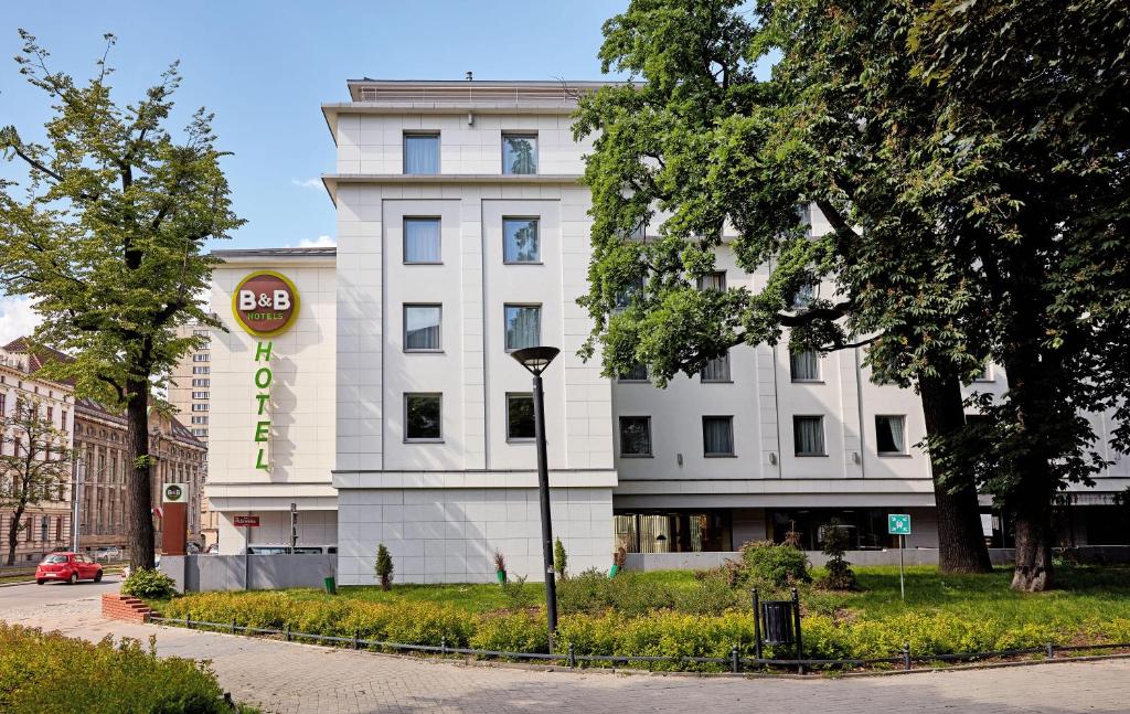 een wit gebouw met een bord ervoor bij B&B Hotel Łódź Centrum in Łódź