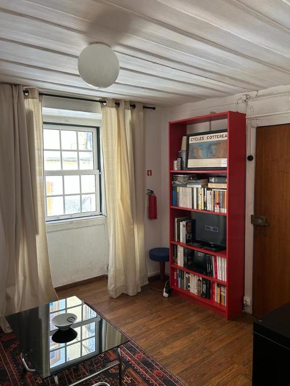 een woonkamer met een rode boekenplank en een raam bij Bairro Alto Flat in Lissabon