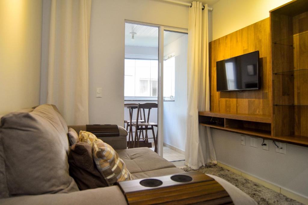 ein Wohnzimmer mit einem Sofa und einem Flachbild-TV in der Unterkunft Condomínio com Piscina Vista Mar na Praia de Vila Nova em Imbituba P2420 in Imbituba