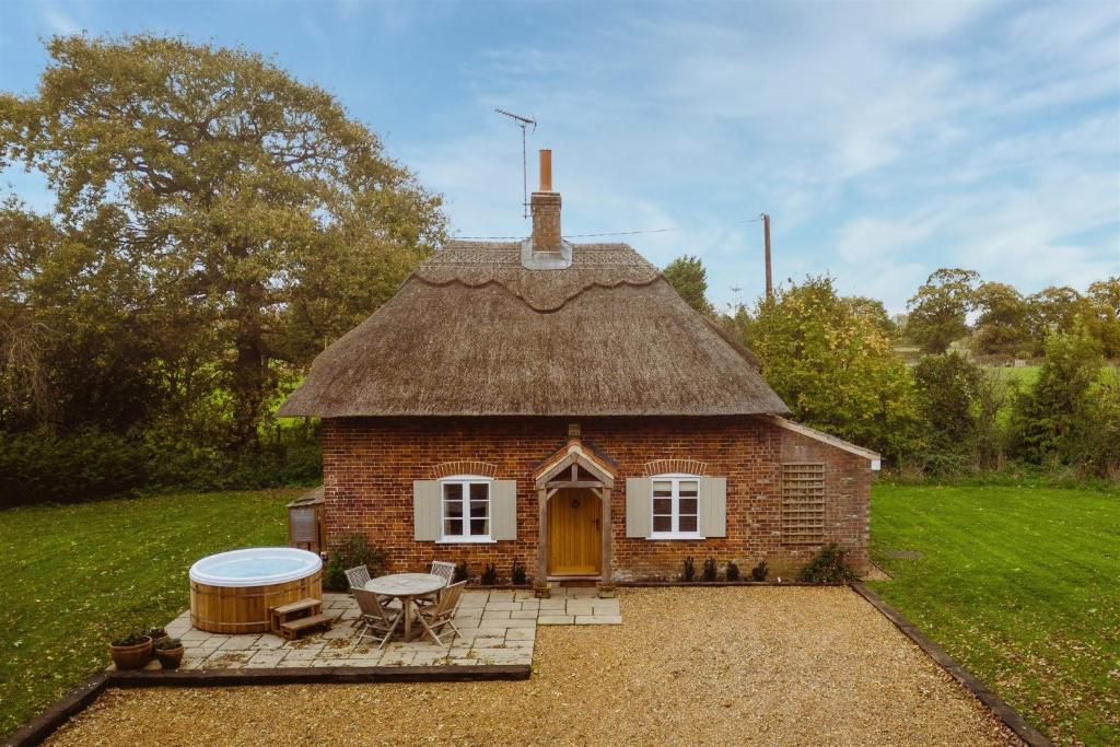 una pequeña casa de ladrillo con techo de hierba en New Lane Cottage en Worstead