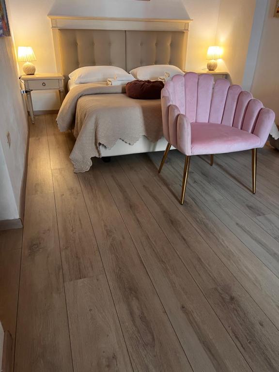 1 dormitorio con 1 cama grande y 1 silla rosa en Affittacamere Louis, en Cagliari