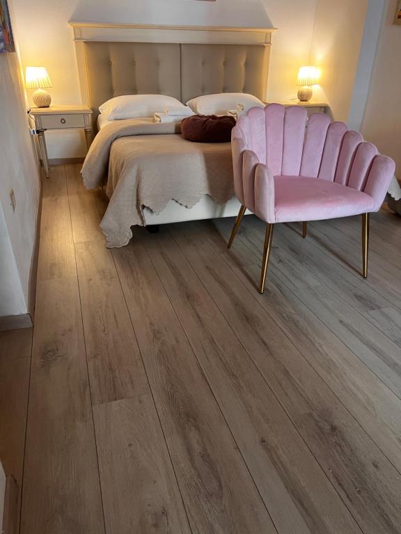 a bedroom with a large bed and a pink chair at Affittacamere Louis in Cagliari