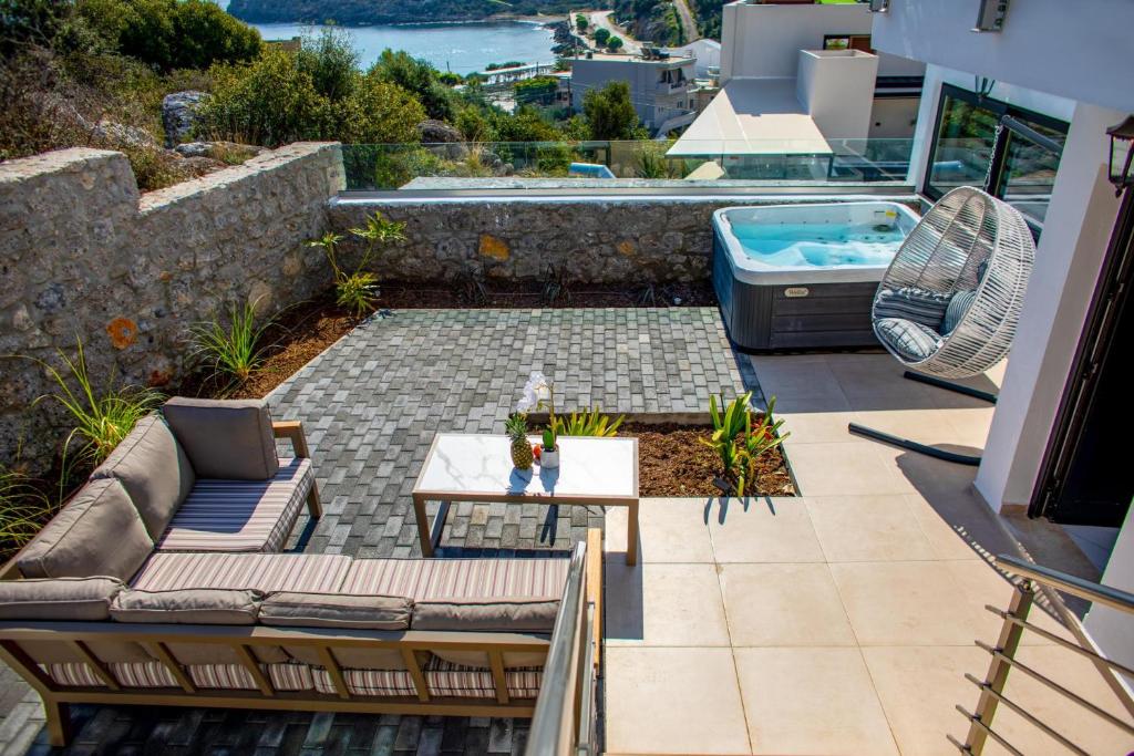 een patio met een bank, een tafel en een bad bij Beach Walk Luxury Suites in Agios Nikolaos