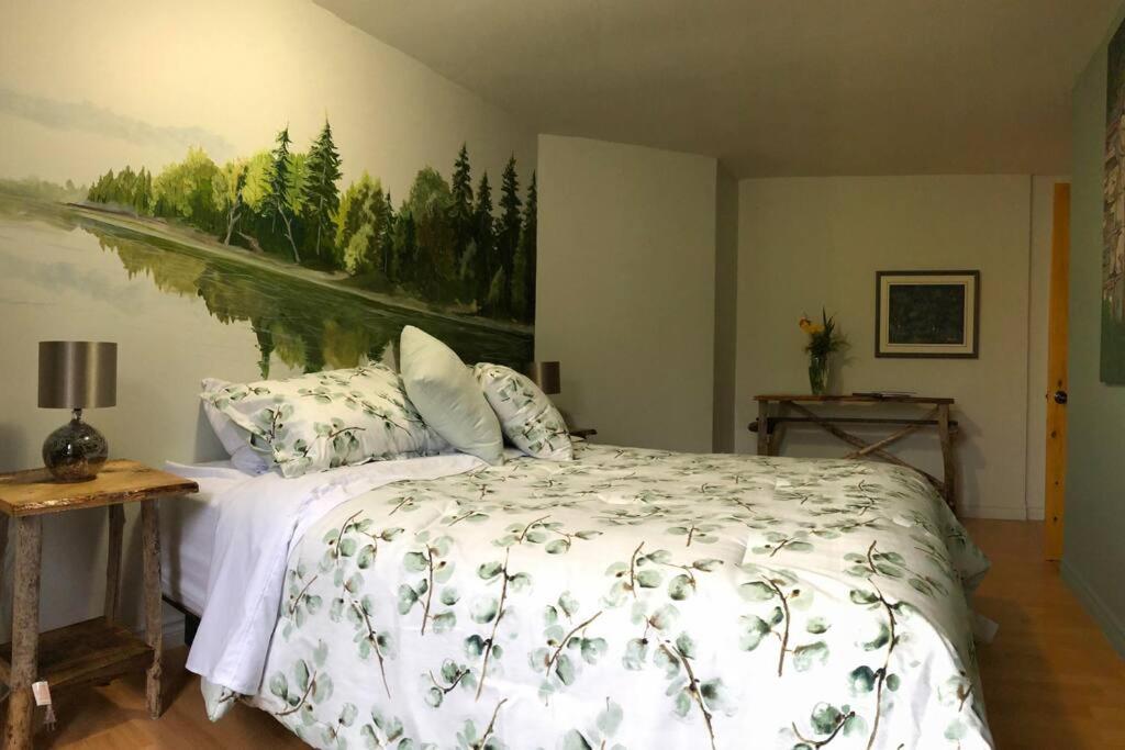 um quarto com uma cama com um quadro na parede em Séjour, Flèche du fjord, vue Saguenay, Mont Valin em Saint-Fulgence