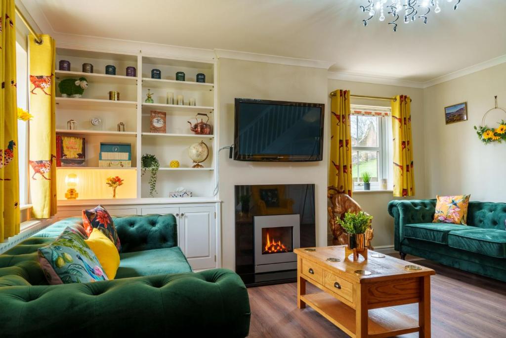 a living room with a green couch and a fireplace at Nannycroft Cottage in Beckermet