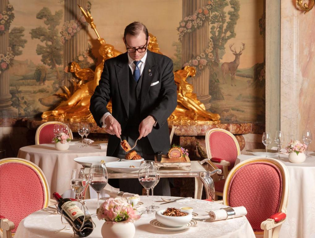 a man in a suit is cutting food on a table at The Ritz London in London