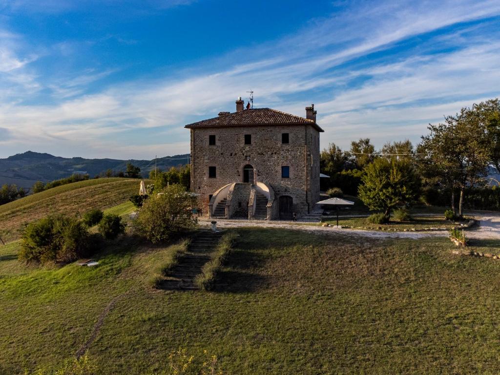 un viejo edificio de piedra en una colina con césped en Palazzo Serre - Natura & Piscina, en San Leo