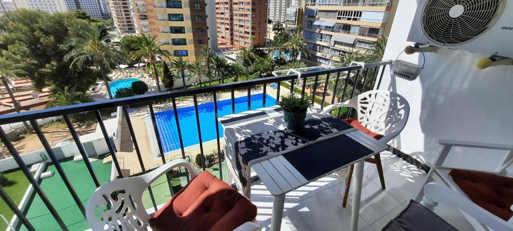 a balcony with a table and chairs and a pool at HAPPY LOiX 1 APARTMENT in Benidorm