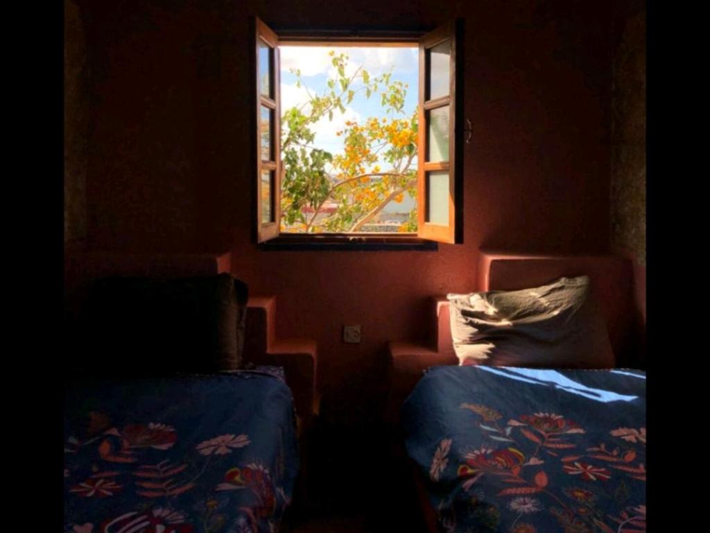 een kamer met 2 bedden en een raam bij Hippie Chic Room 2 in Sidi Kaouki