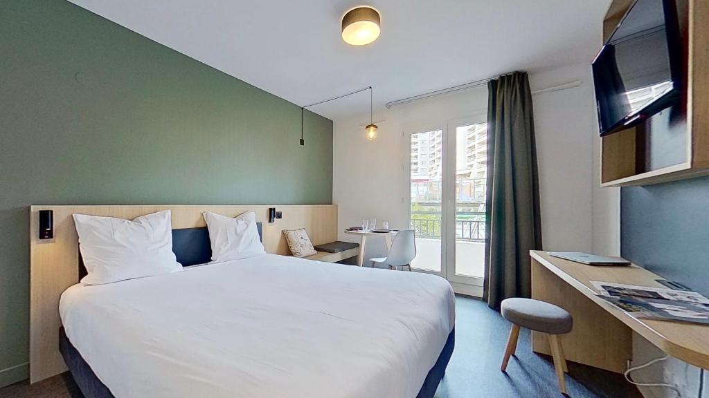 una camera d'albergo con un grande letto e una scrivania di City Résidence Paris Saint-Maurice a Saint-Maurice