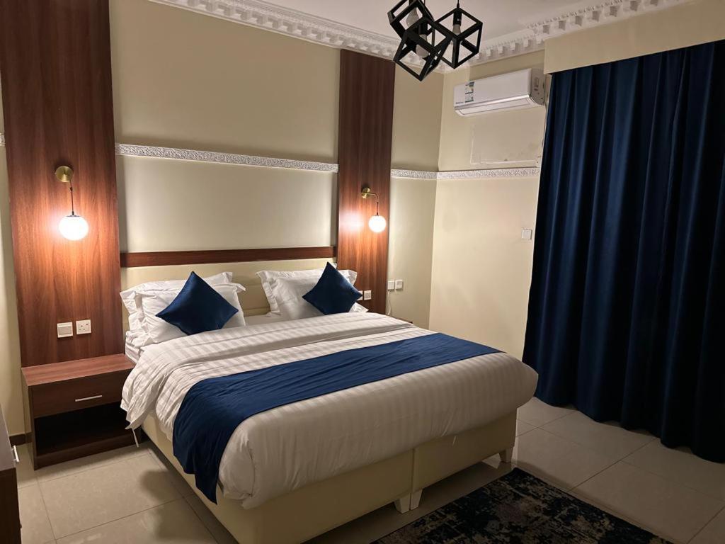 1 dormitorio con 1 cama grande con almohadas azules en المبيت 3 للشقق الفندقية en Abha