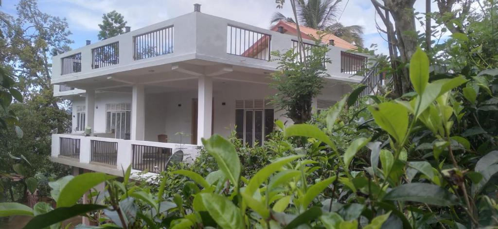 uma casa branca com um alpendre à volta em White Eco Villa em Kandy