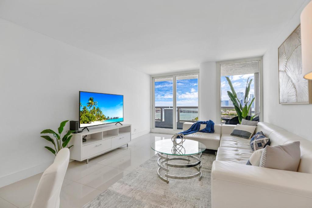 Il comprend un salon blanc doté d'un canapé et d'une télévision. dans l'établissement Downtown SeaClusion, à Miami