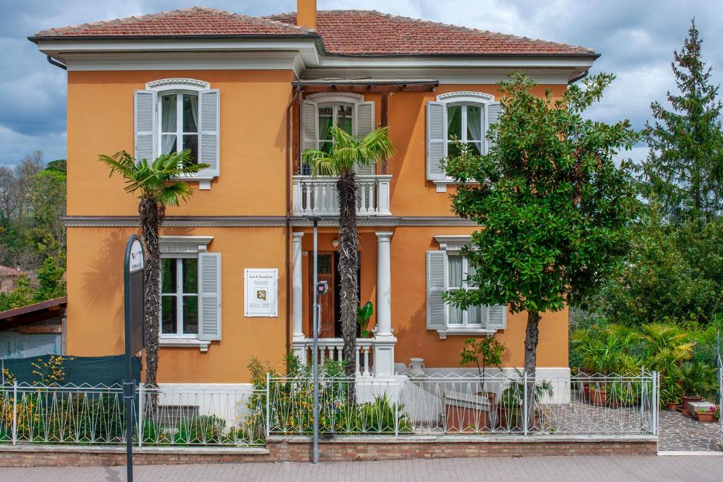 una casa de naranjos con palmeras delante de ella en Villa Liberty Urbino, en Urbino