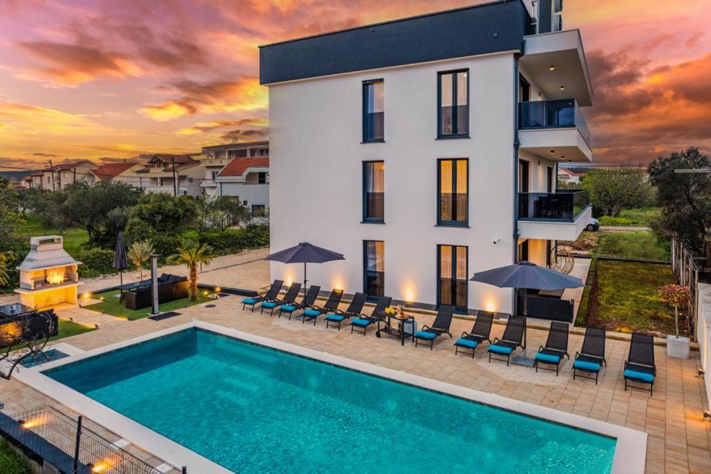 una villa con piscina di fronte a un edificio di Villa Ivani a Sukošan (San Cassiano)