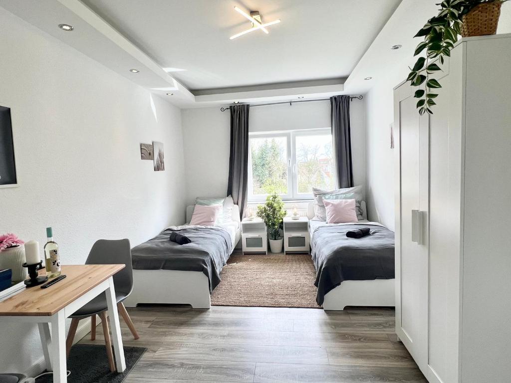 Habitación con 3 camas, escritorio y ventana. en Helle, gemütliche Ferienwohnung in Bremerhaven en Bremerhaven